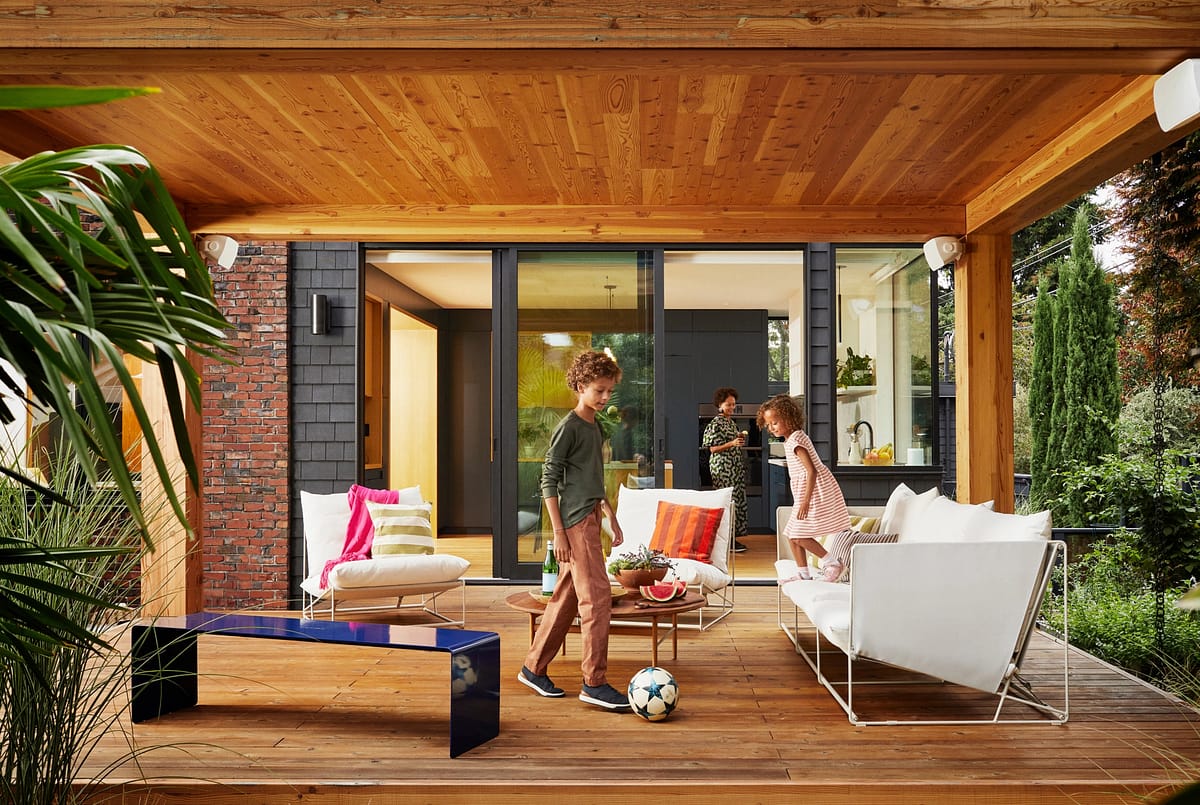 An outdoor patio with in-ceiling speakers and two children playing.