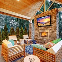Patio with an outdoor TV above a fireplace