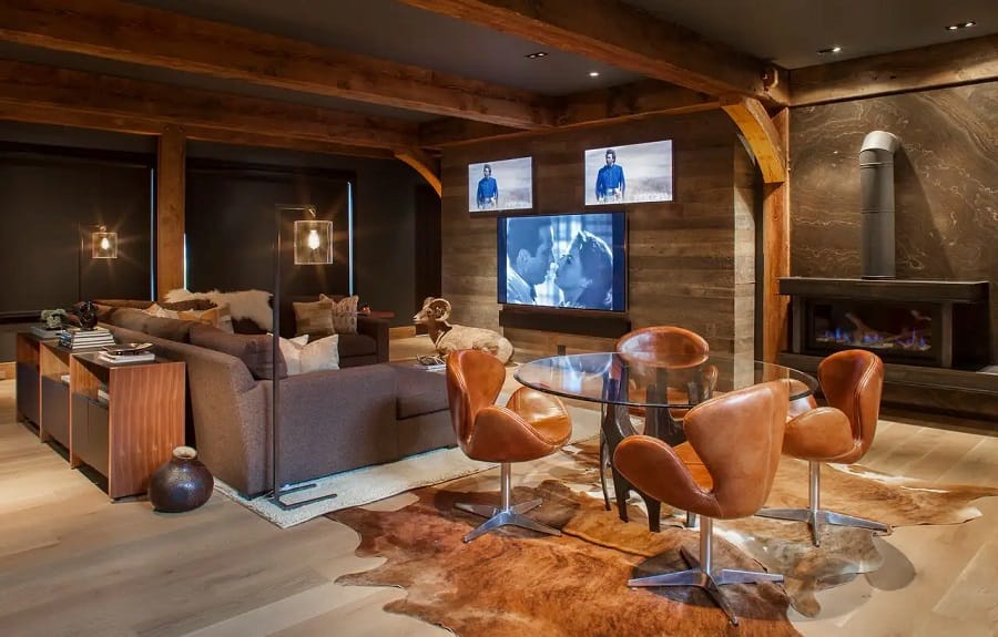 Modern luxury media room with rustic beams and gas fireplace.