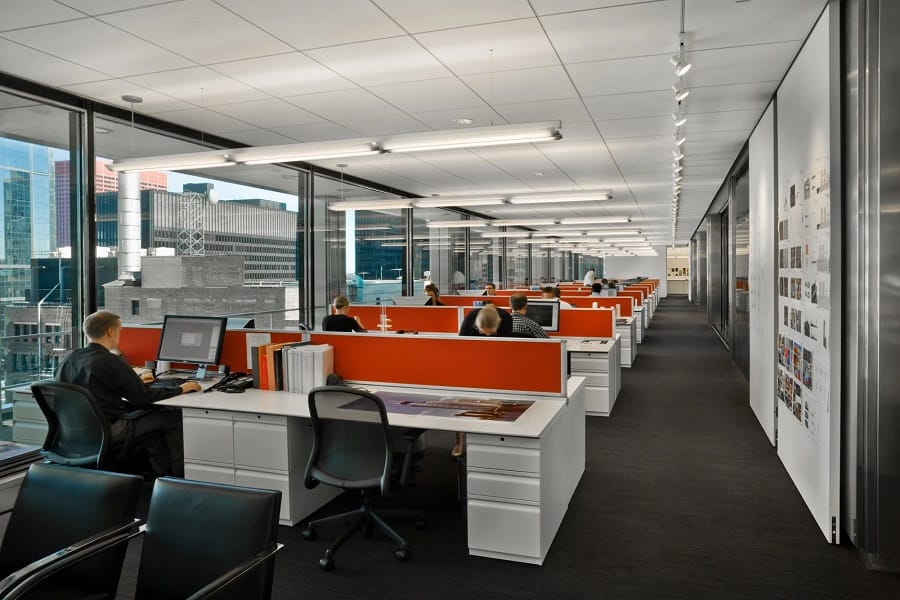 Hybrid office with multiple workstations, bright and cheery colors, and large windows overlooking a cityscape.